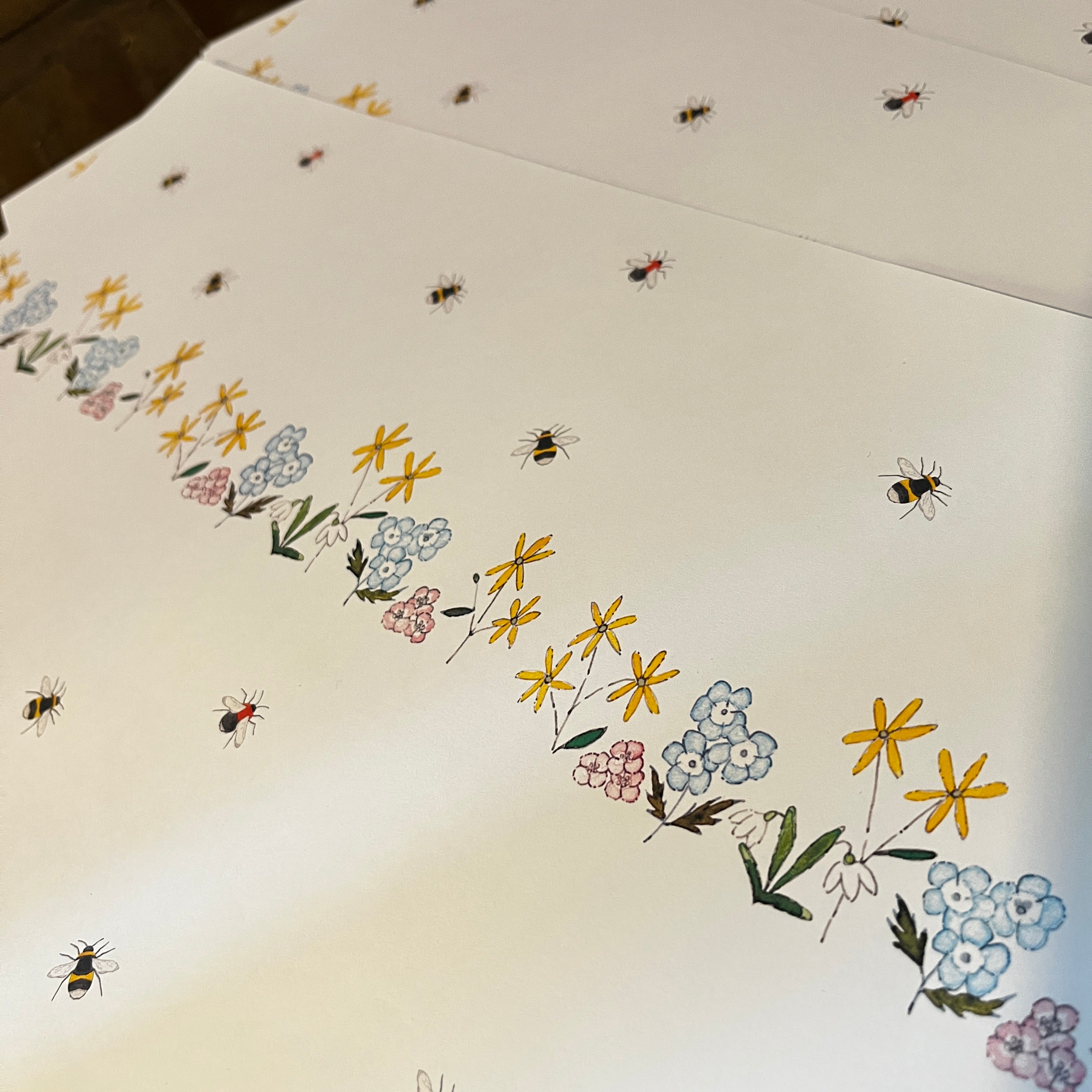 A close-up of a white paper wrapping paper featuring a delicate repetition of illustrated wildflowers and bumblebees.