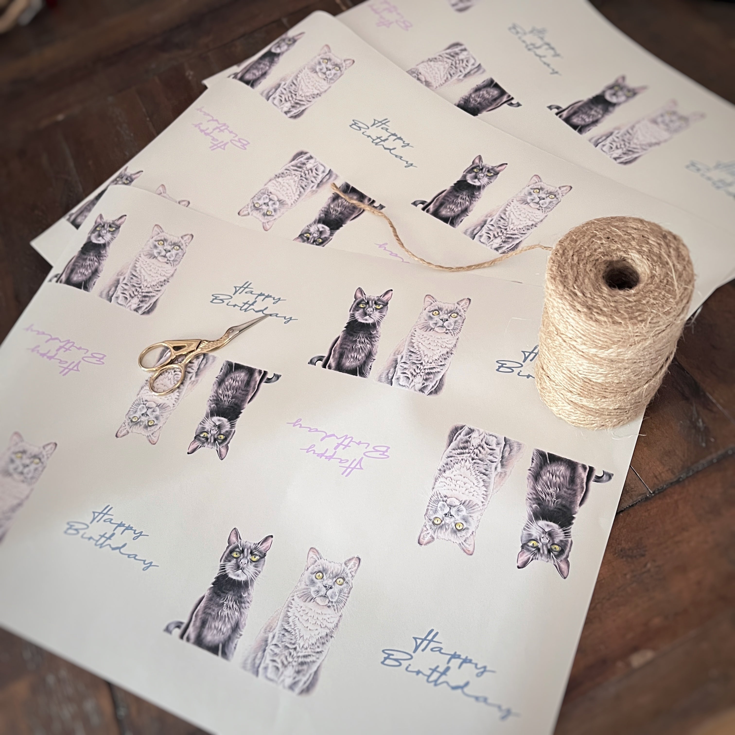 Cat ‘happy birthday’ wrapping paper with an illustration of a grey cat and black cat sitting next to each other