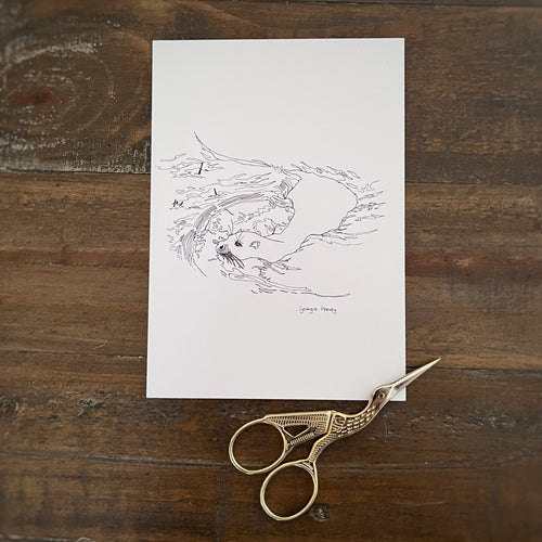 Black and white hand drawn British otter postcard for colouring in with small scissors next to it on wooden table 