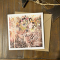 A square greeting card featuring a detailed illustration of a brown rabbit among autumn foliage, displayed on a rustic dark wood surface with a kraft envelope behind it.